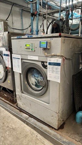 Front-load washer installed on a working laundry plant floor