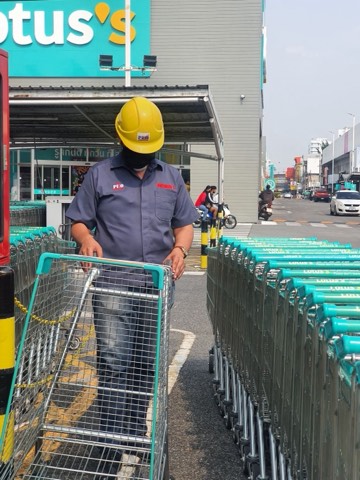 Technician moving a green cart fleet outside a Lotus's store