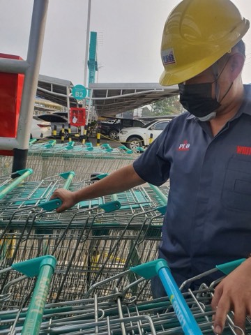 Uniformed technician servicing shopping carts in a car park