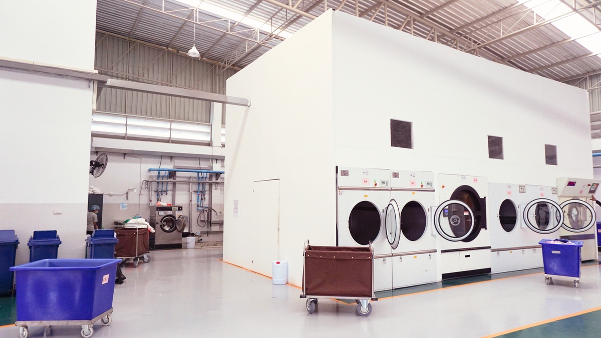 Operating laundry plant floor with industrial washing and processing equipment in rows