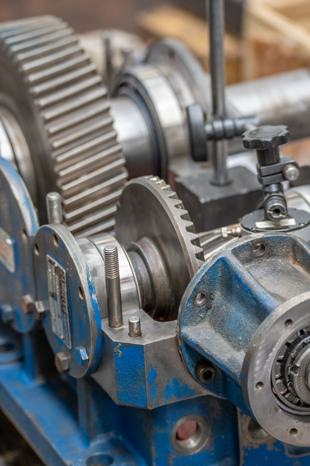 Close-up of industrial gear assemblies, bearings, and a blue machine housing on a maintenance bench