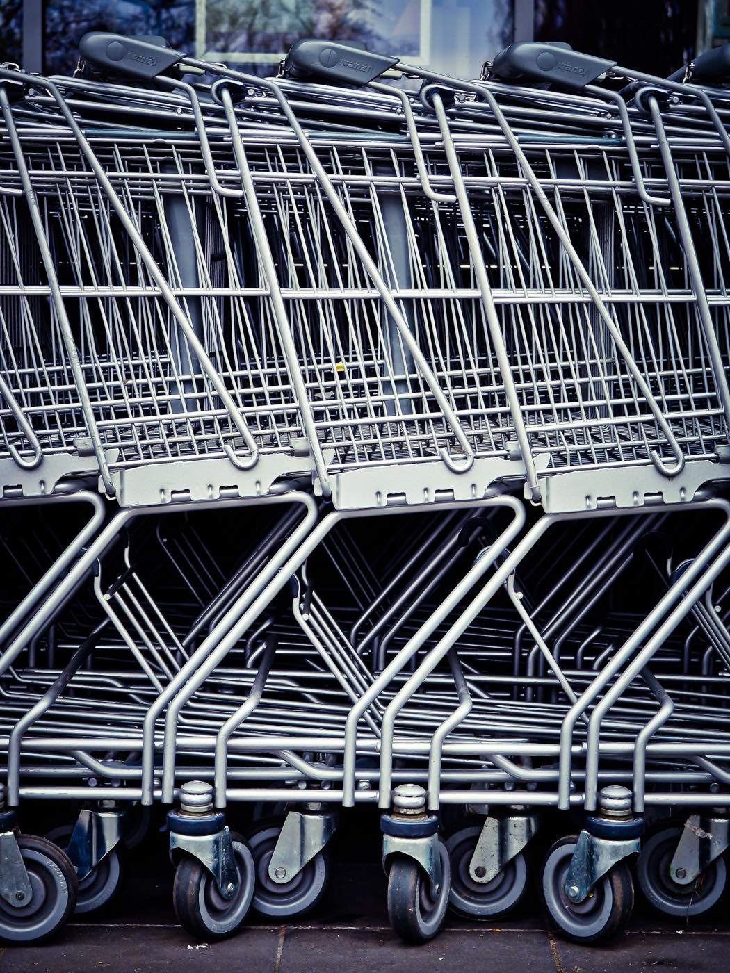 Nested row of steel shopping carts seen close up, caster wheels aligned in the foreground