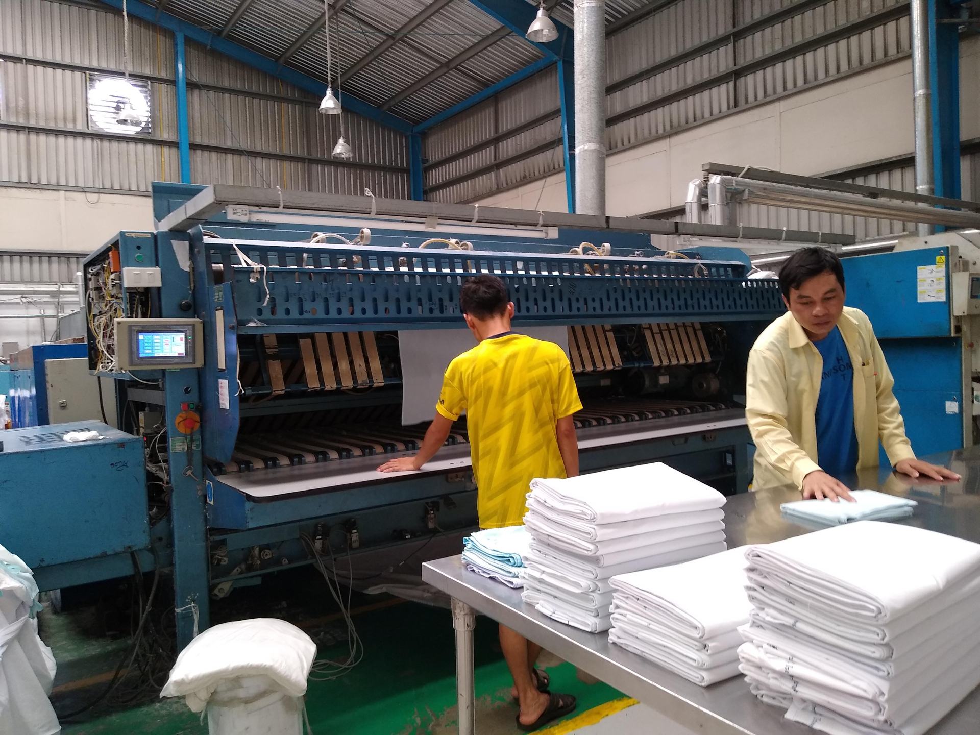 Ideal Laundry staff finishing and folding clean hospital linen on the plant floor