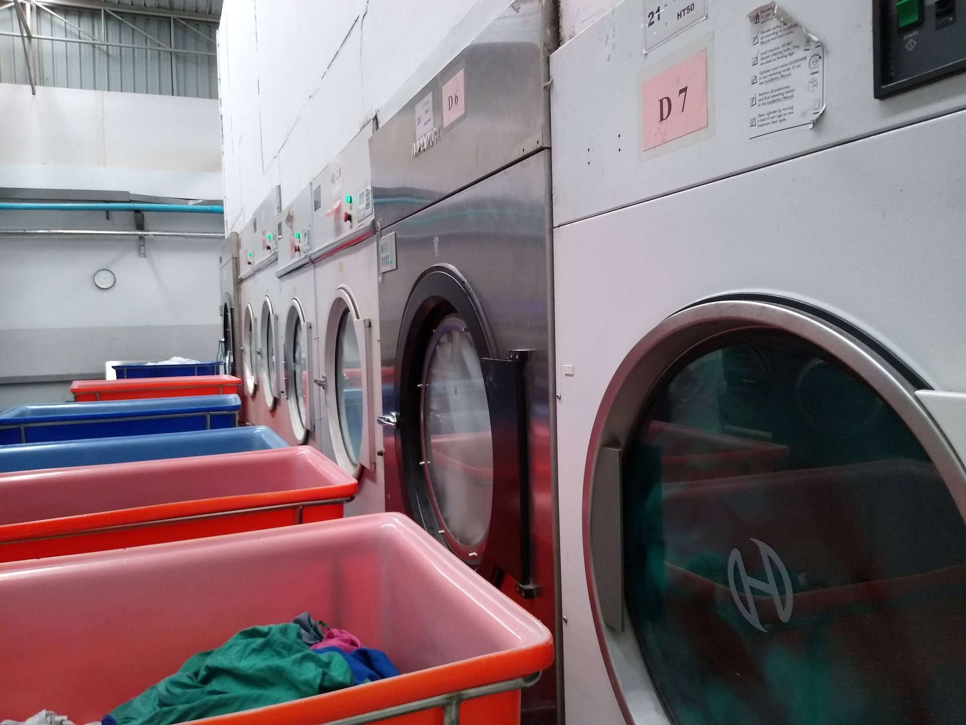 Bank of industrial washer-extractors and dryers on Ideal Laundry's own hospital-linen plant floor