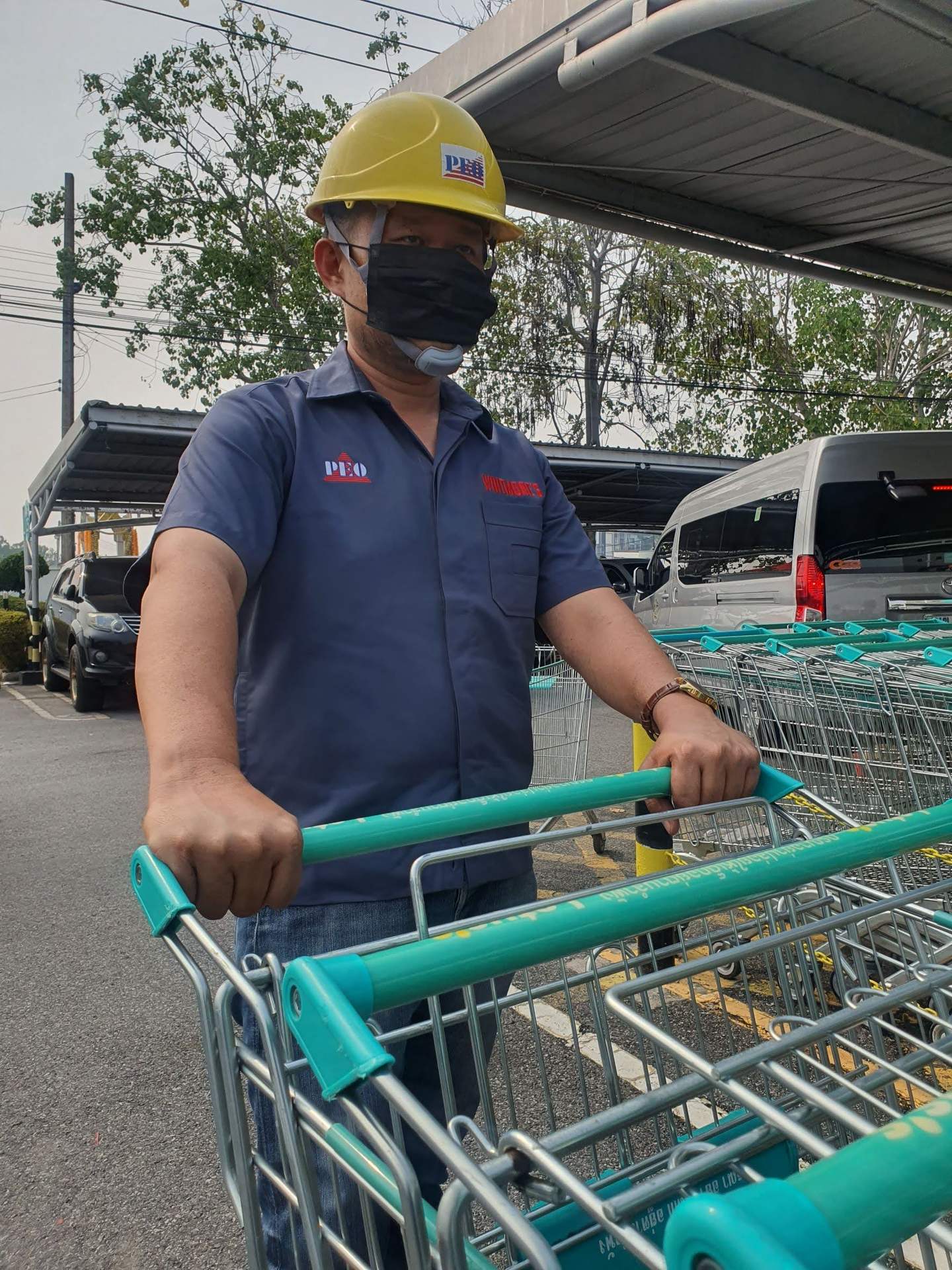 PEO Tech technician in PEO uniform servicing Lotus's shopping trolleys in the store car park