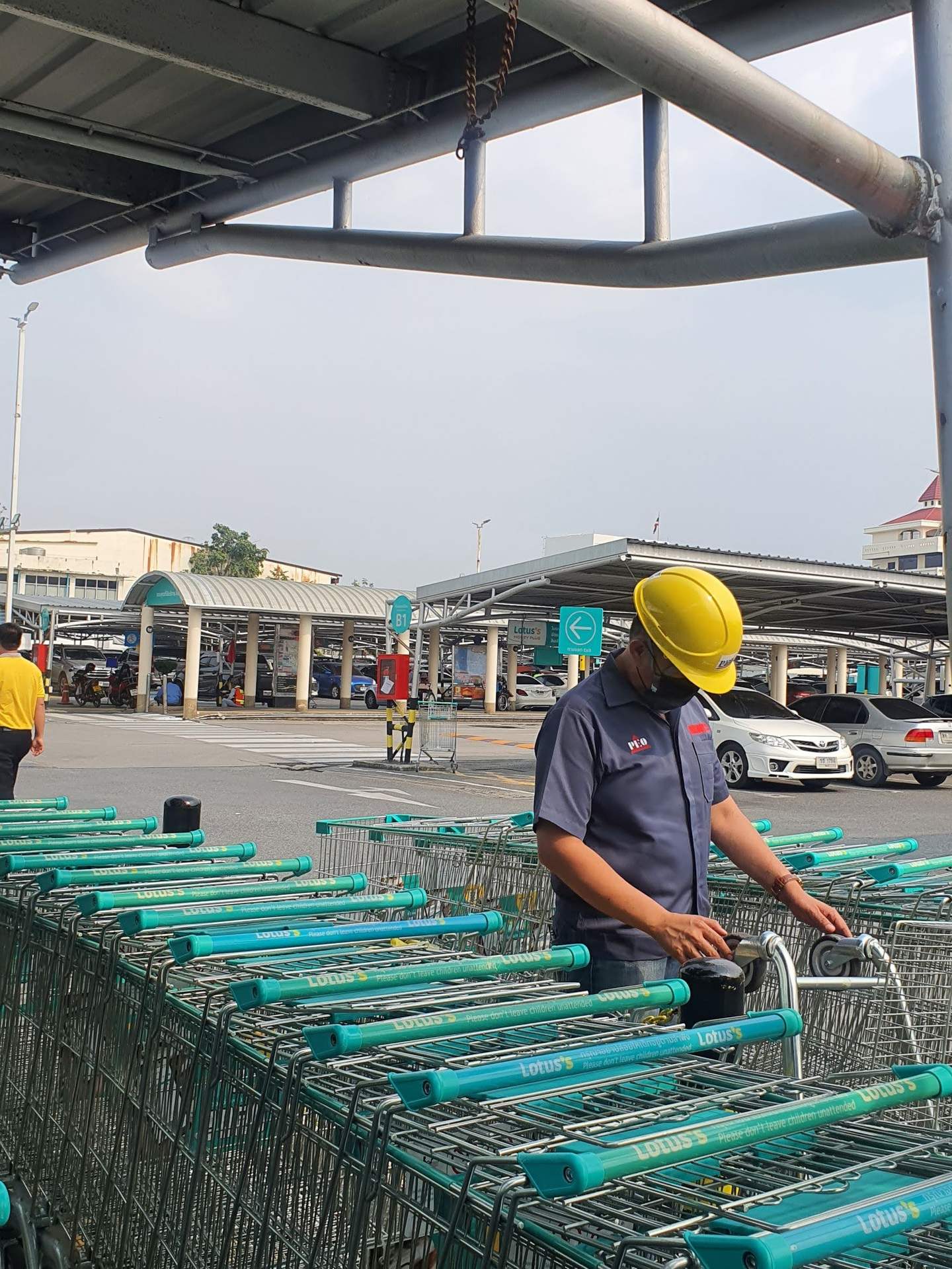 PEO Tech technician in PEO uniform inspecting the casters and frame of Lotus's shopping trolleys before servicing